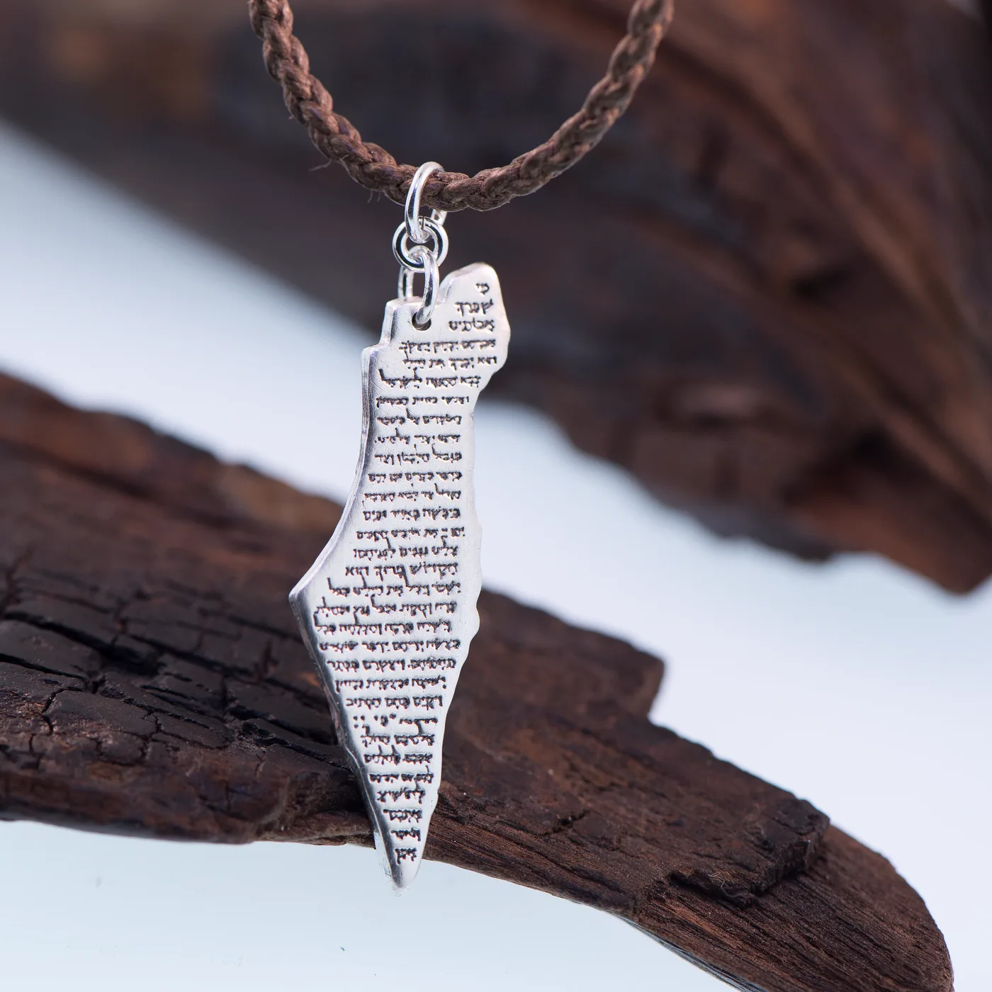 Map of Israel pendant in silver, the prayer text pressed across its face, on a leather cord