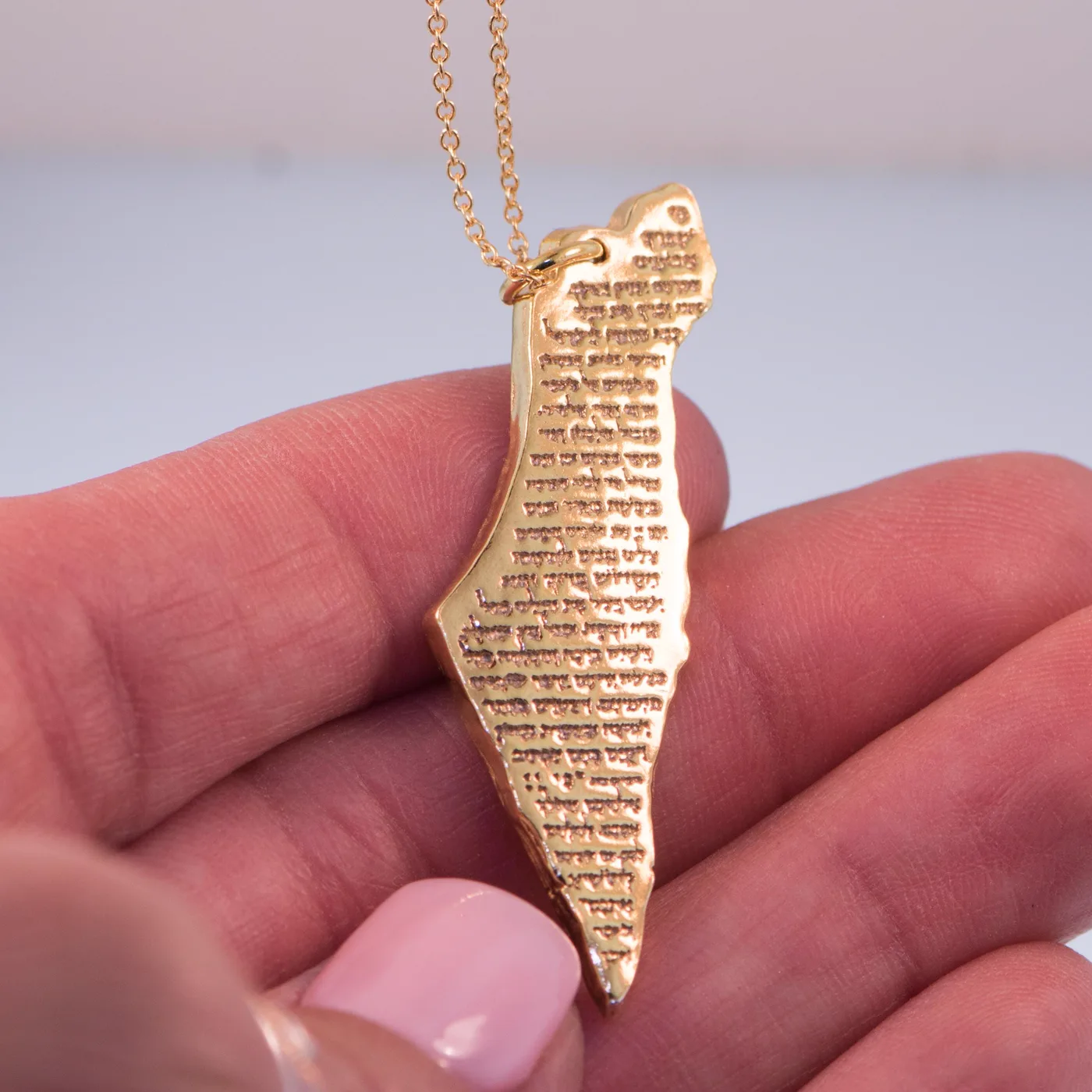 The same pendant in gold, resting on charred wood