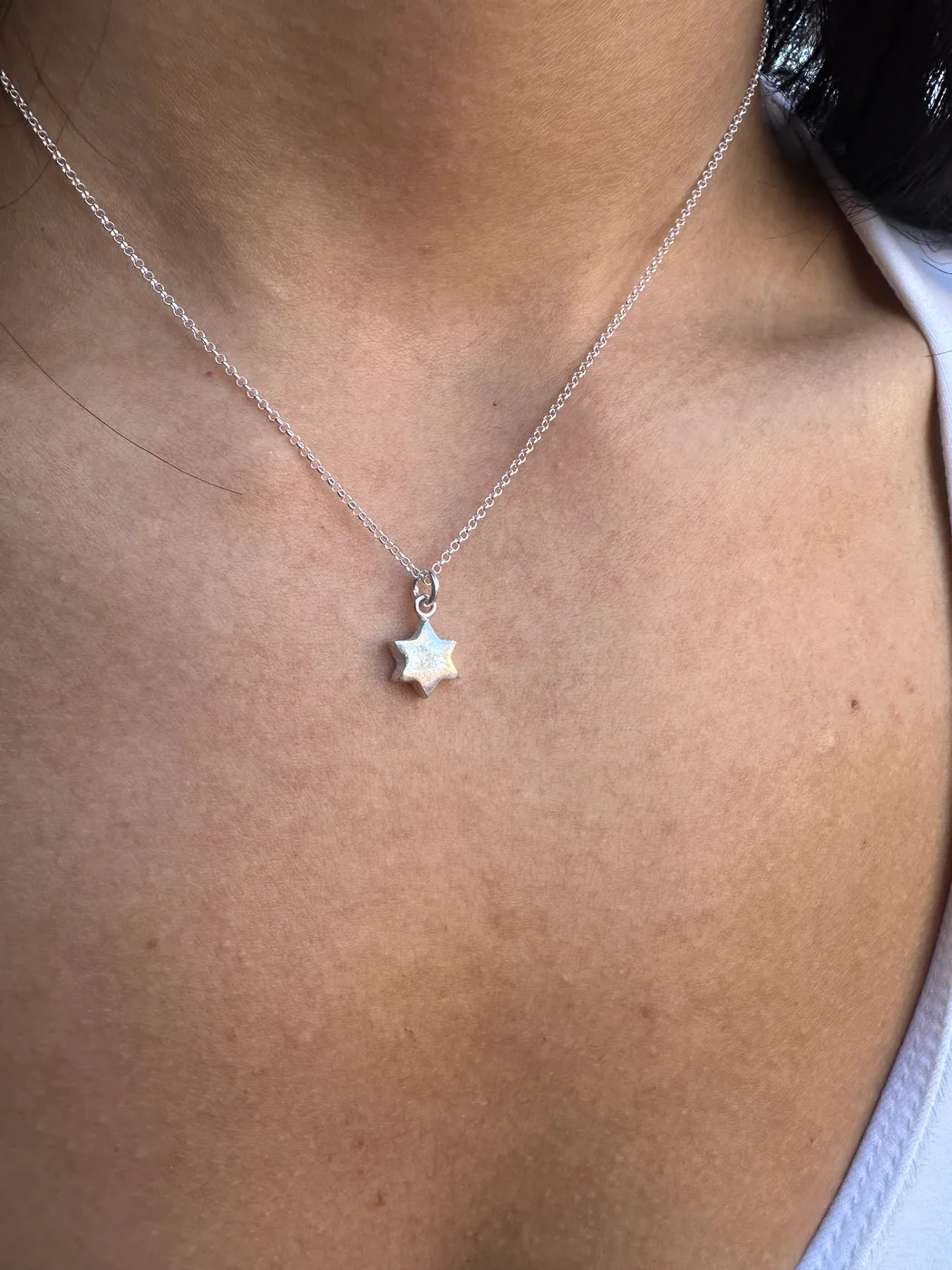 Teeny tiny Star of David charm in silver, worn at the collarbone