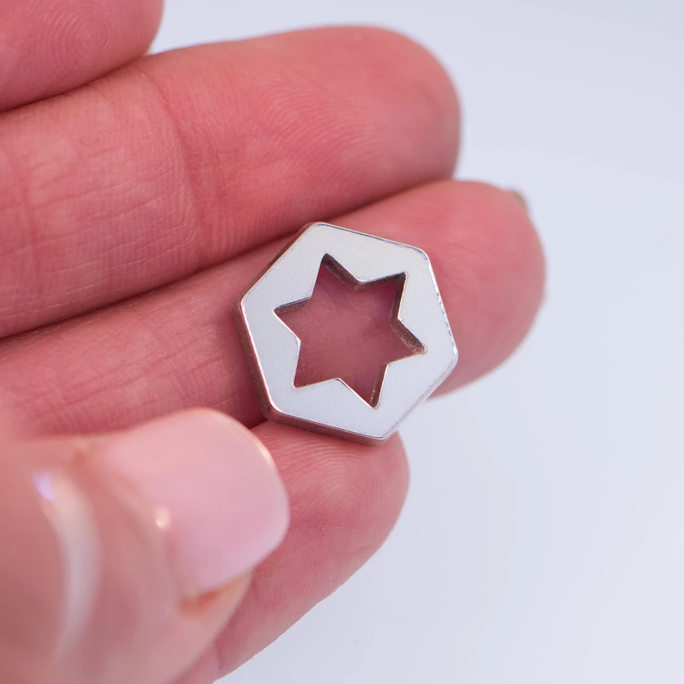 Minimalist Star of David charm held, showing its true size