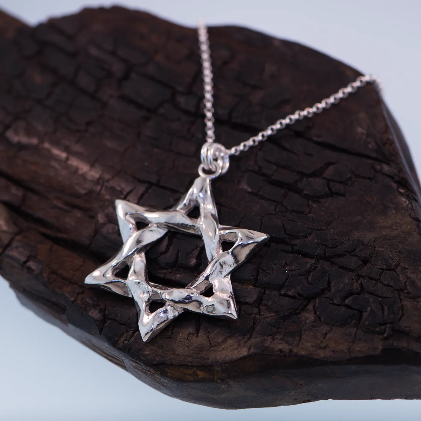 Hammered textured Star of David pendant in sterling silver, on charred wood
