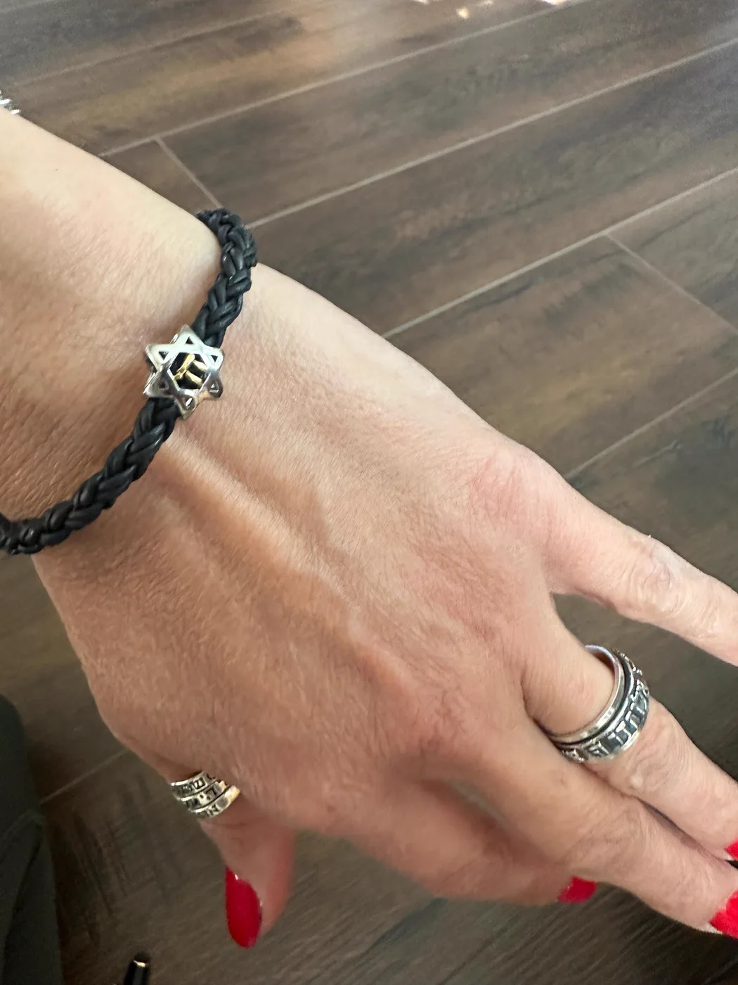 The bracelet worn on a wrist, braided leather with the silver star bead