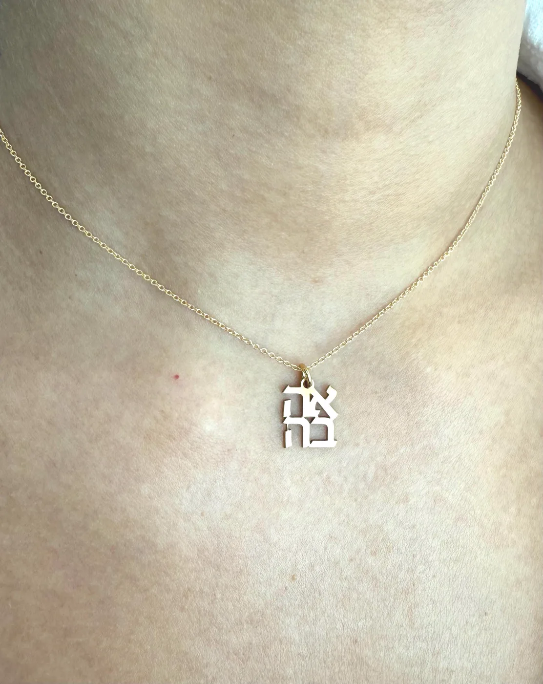 The AHAVA charm worn on a fine chain at the collarbone