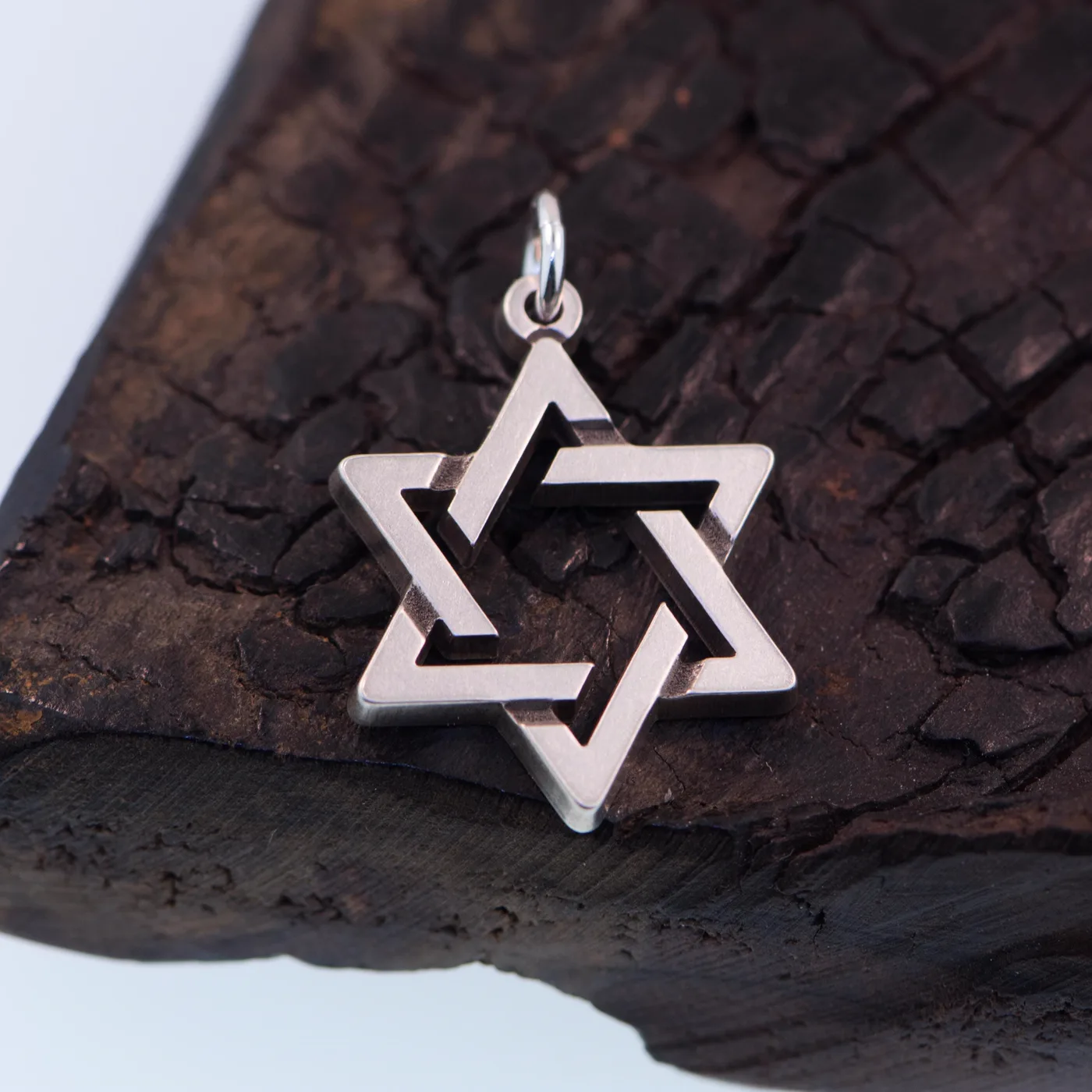 Open interlocking Star of David pendant in sterling silver, on charred wood