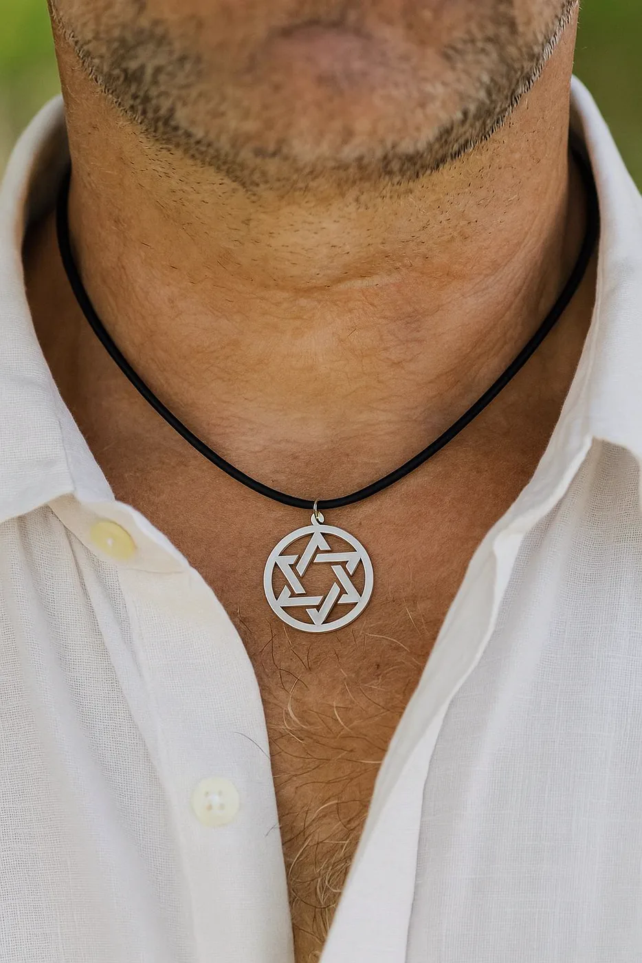 The medallion worn at a man's collar over a white shirt