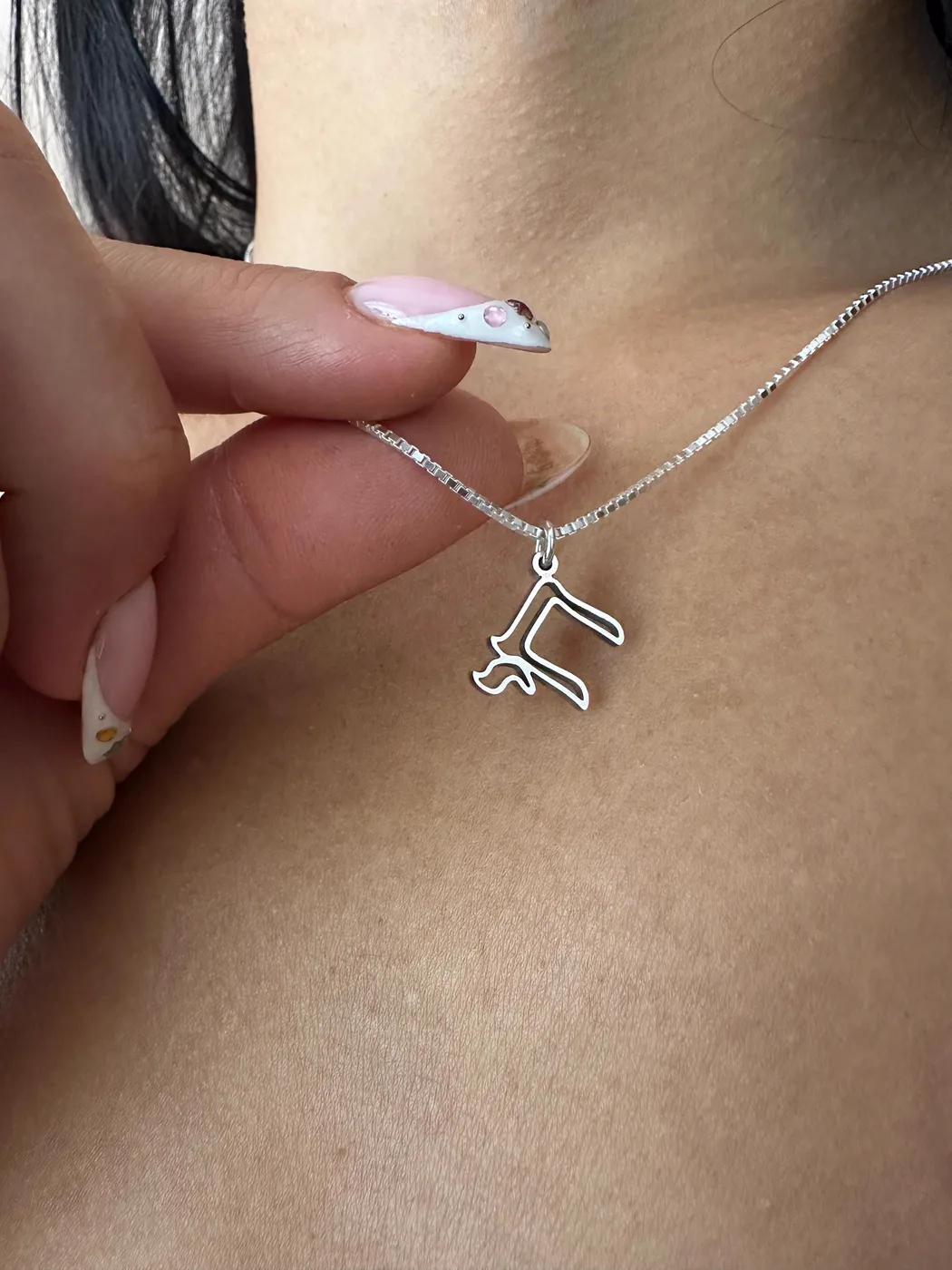 The open Chai charm held against the skin on a fine chain
