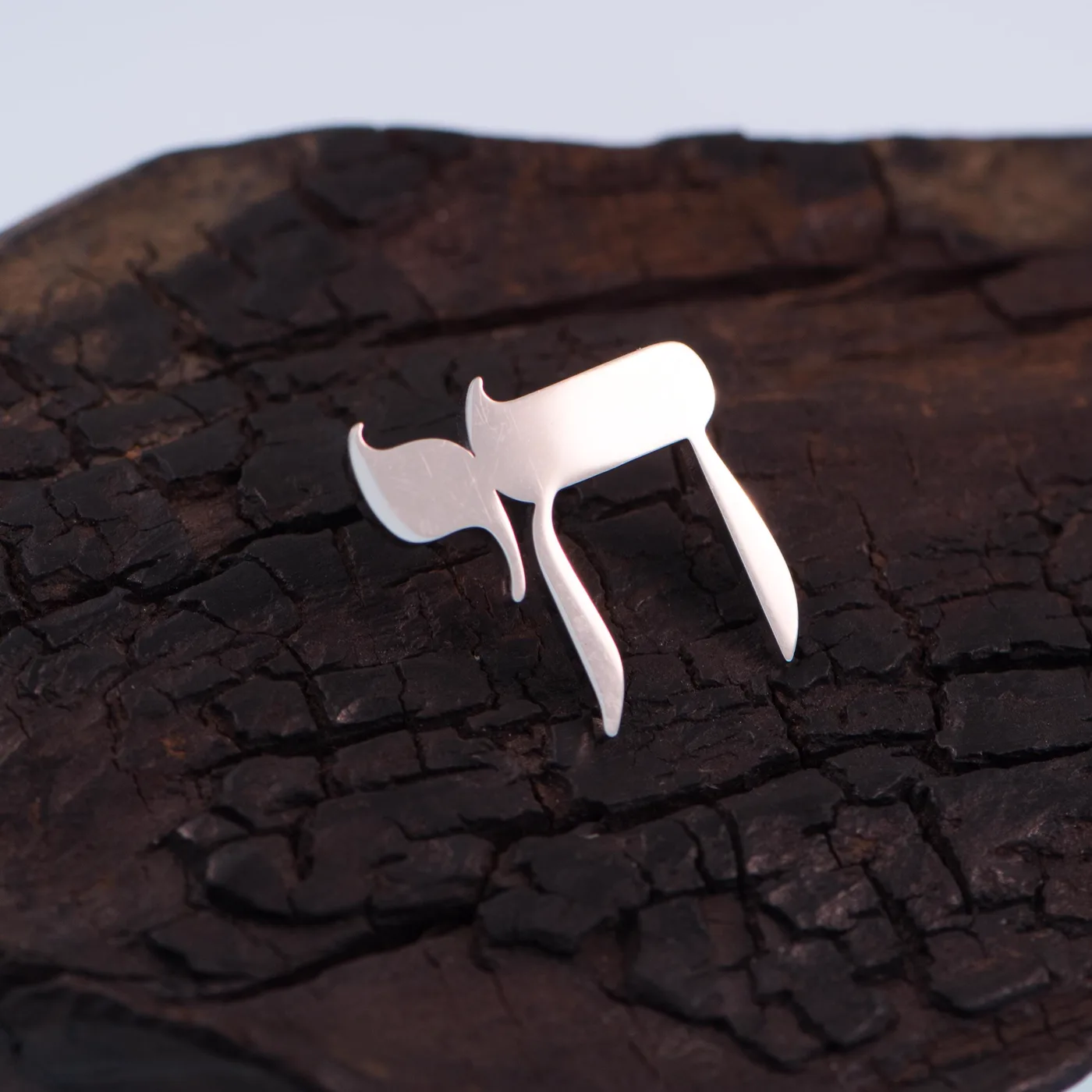 Chai Lapel Pin in silver, on charred wood
