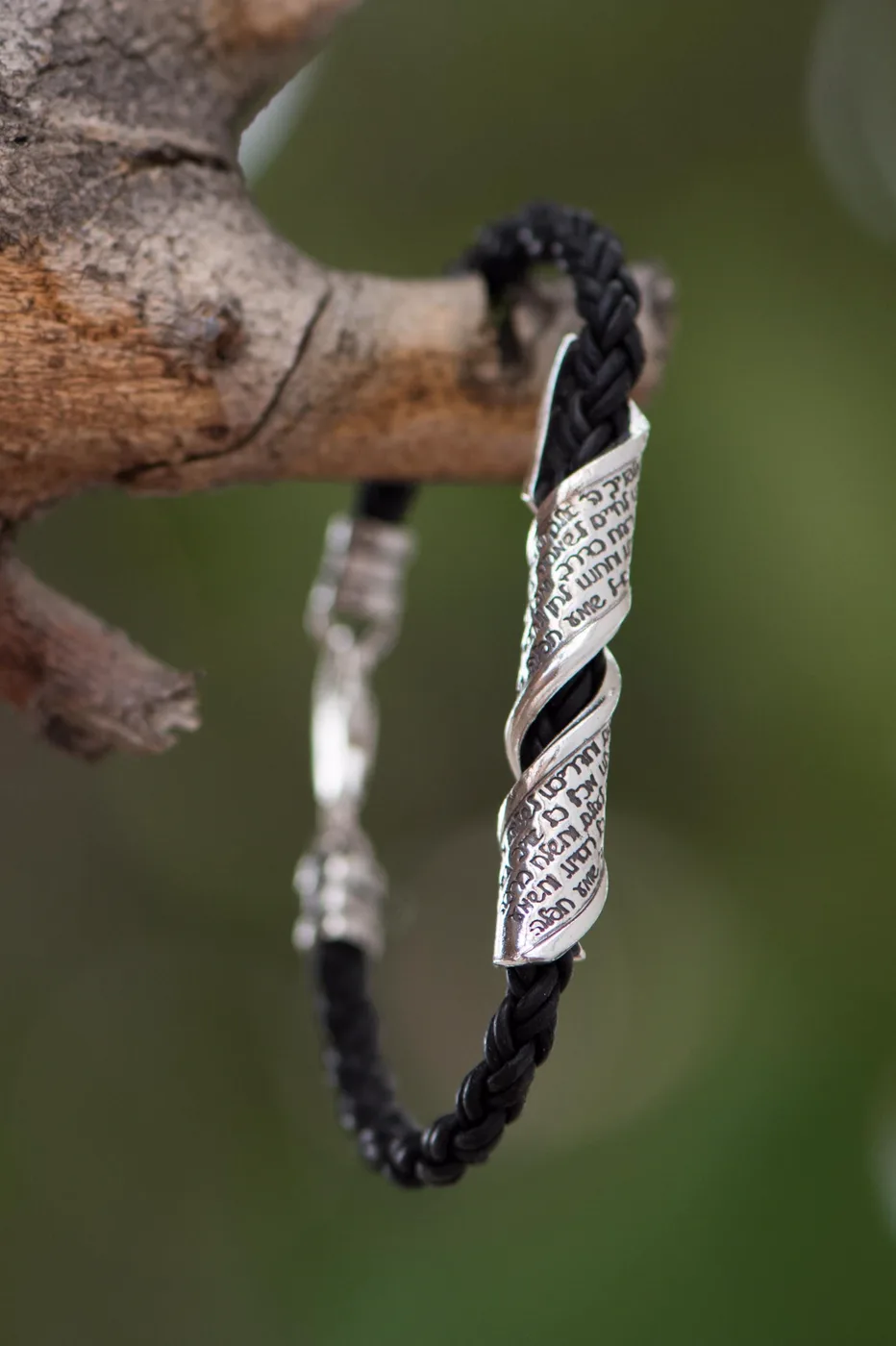 Traveler's Prayer bracelet hanging from a branch, the twisted silver plate inscribed with the prayer